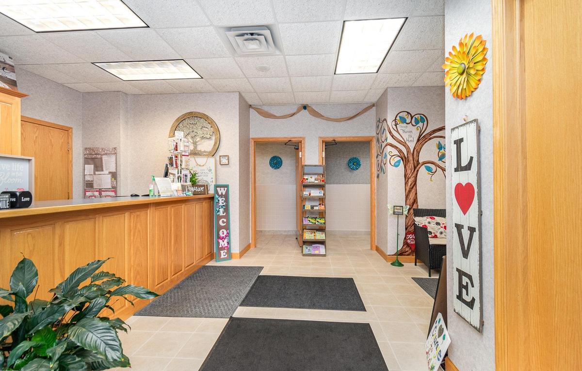 The lobby at Blooming Consultants, looking past the oak reception counter to a painted tree on the far wall and a tall wooden sign spelling LOVE.