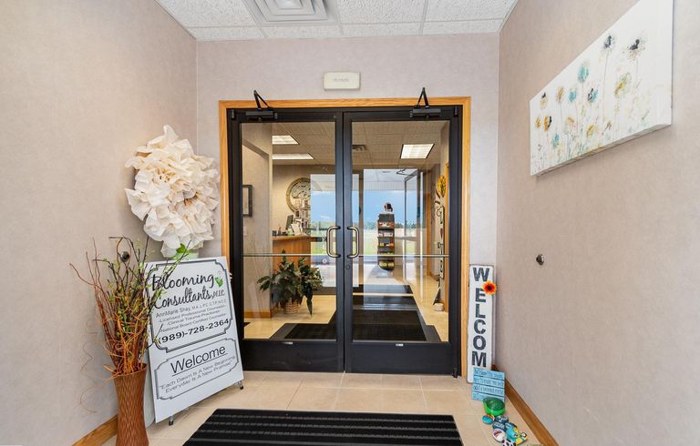 The entrance at Blooming Consultants, looking in through the inner glass doors past a paper flower wall sculpture and a welcome sign.