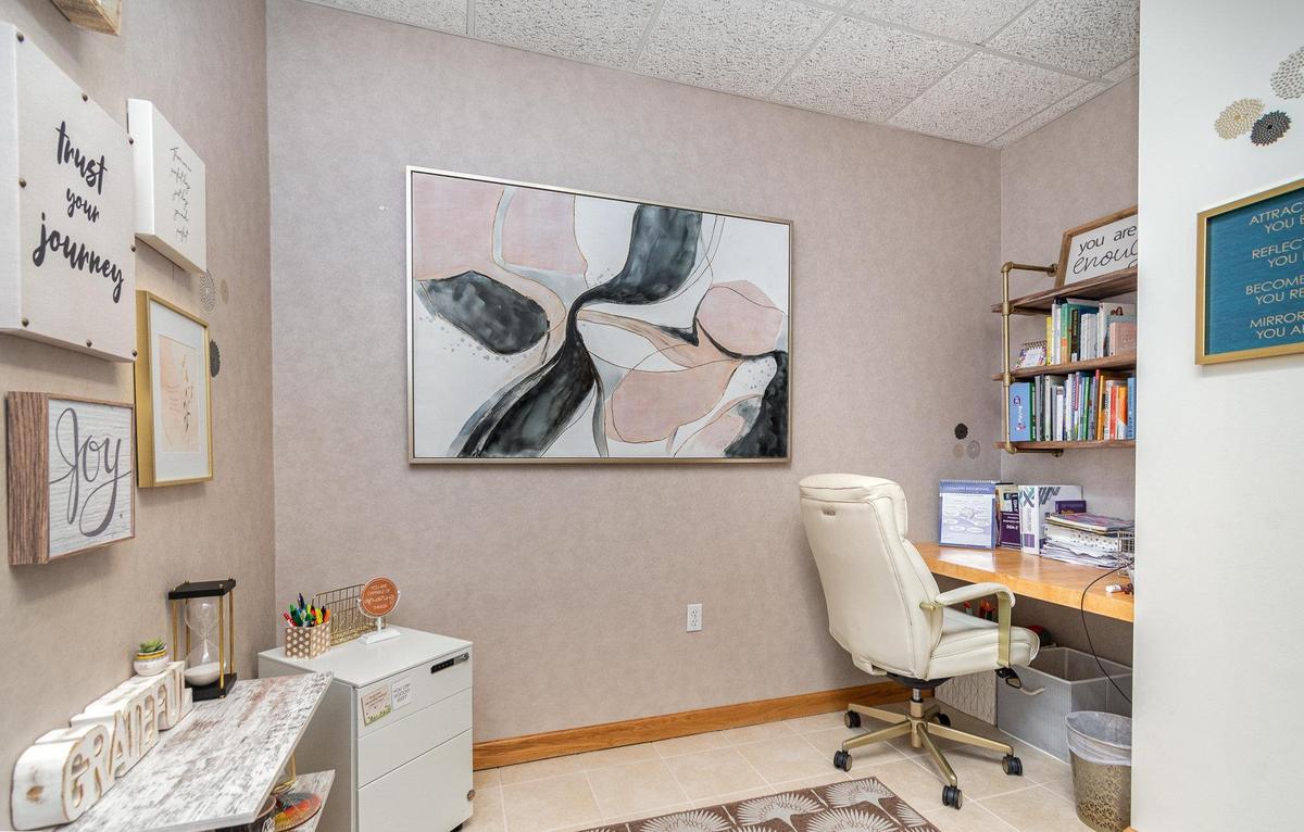 A private office at Blooming Consultants, with a desk, a leather chair and a large abstract canvas.