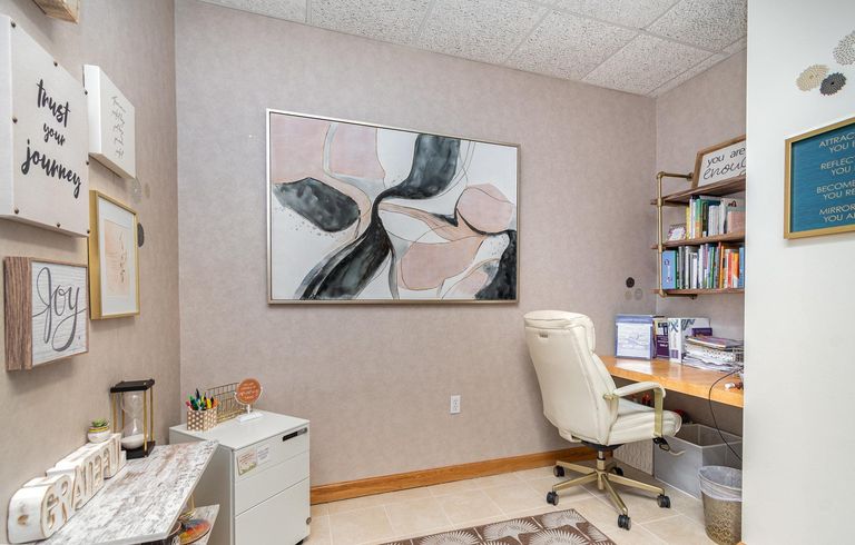 A private office at Blooming Consultants, with a desk, a leather chair and a large abstract canvas.