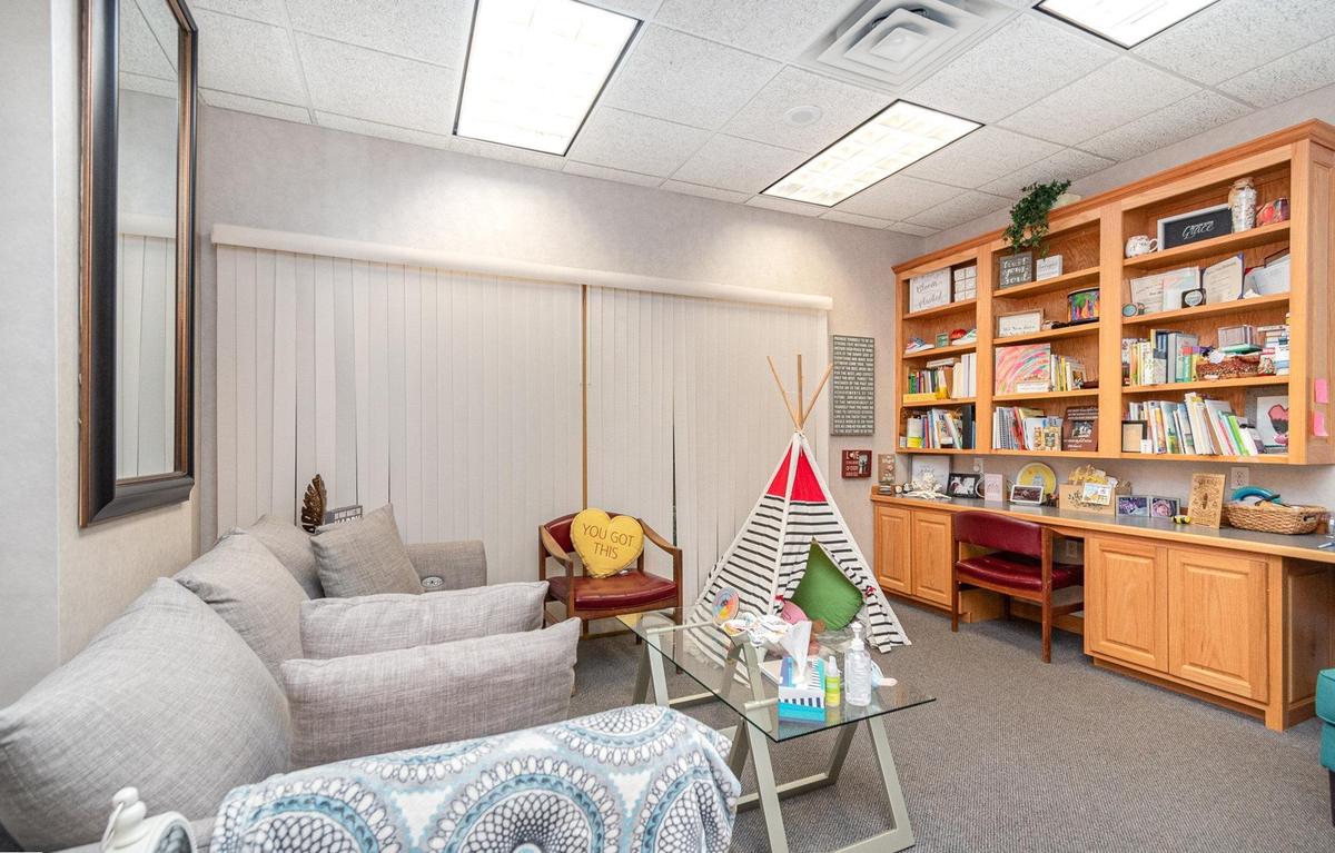 A therapy room at Blooming Consultants, with a sofa, a low table and shelves of books.